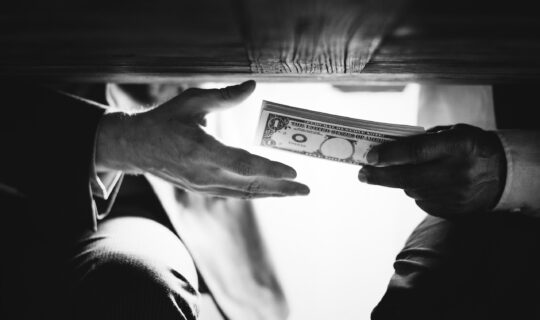 Hands passing money under the table corruption and bribery